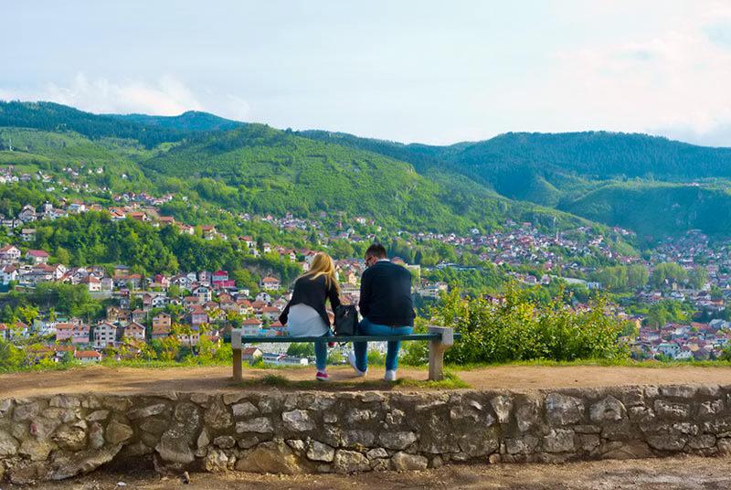 Pariskunta istuskelee penkill Sarajevossa