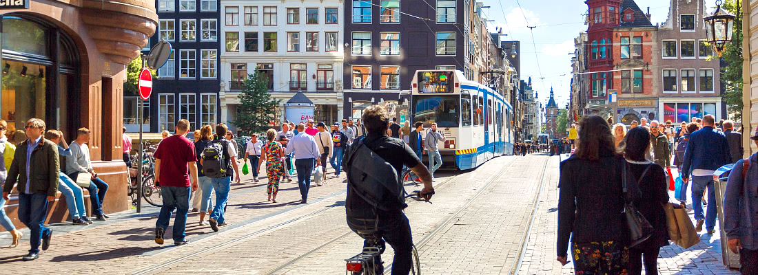 Kävelijöitä, raitiovaunu ja pyöräilijöitä Amsterdamissa