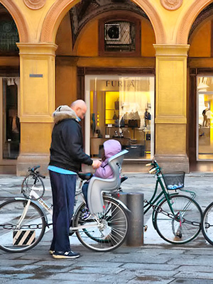 Lapsi polkupyöräistuimessa Piazza Galvani -aukiolla