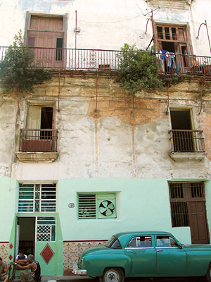 Rakennuksen julkisivu ja vanha amerikkalainen auto Havannassa.